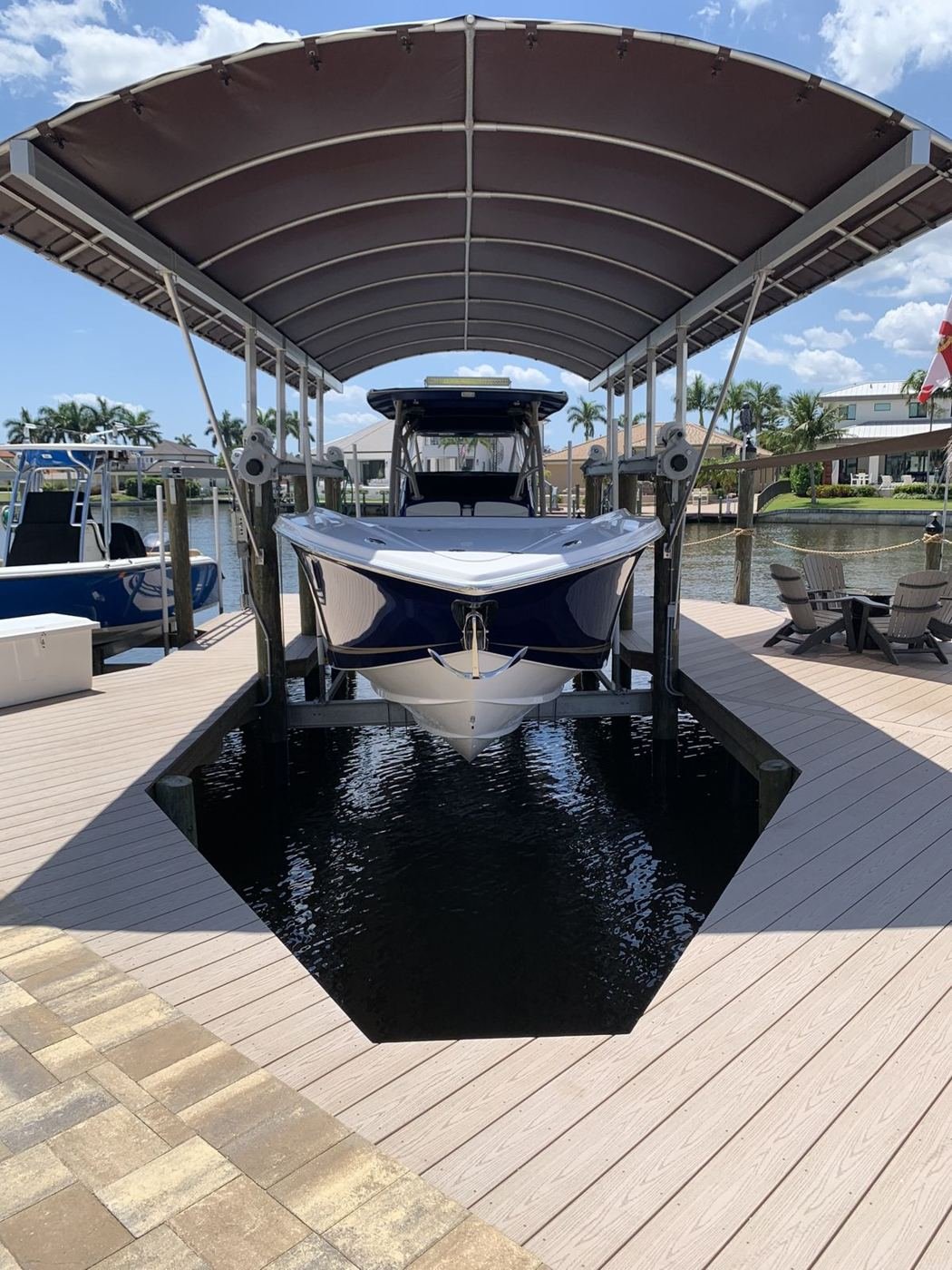 Navy center-console raised on a covered boat lift in a vinyl dock slip