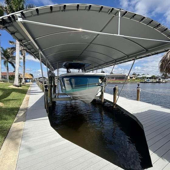 Teal center-console on a boat lift under a grey canopy