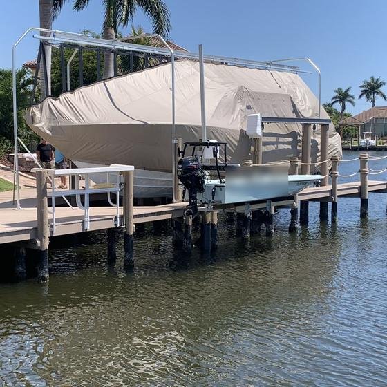 Flats skiff on a piling lift beside a covered boat lift