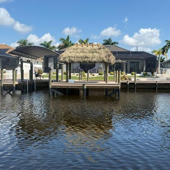 Vinyl dock with a tiki hut and covered boat lift seen from the canal