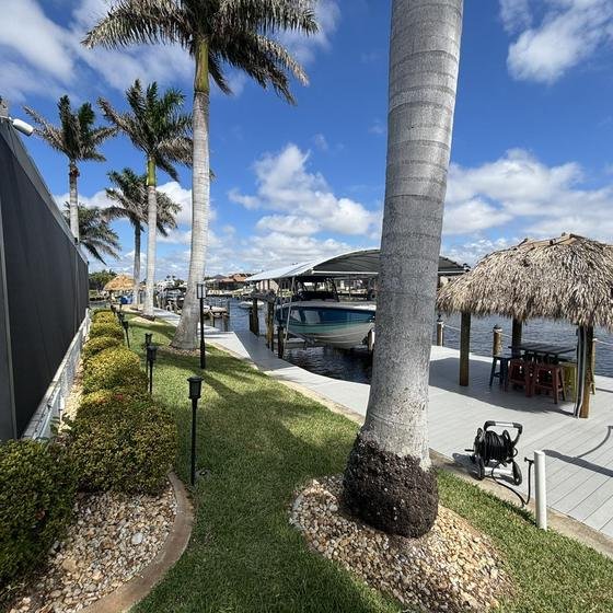 Tiki hut on a Slate Gray vinyl dock beside a covered lift and royal palms