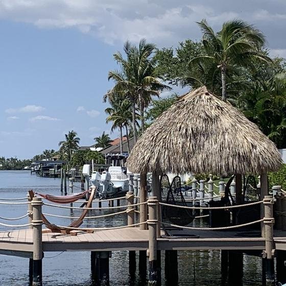 Tiki hut on a vinyl dock with rope railing and a hammock